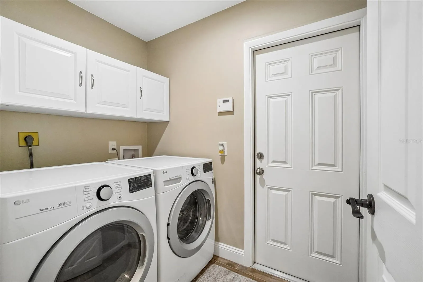 Laundry Room – The dedicated laundry room offers side-by-side laundry appliances, overhead cabinetry for added storage, and a convenient exterior access door.
