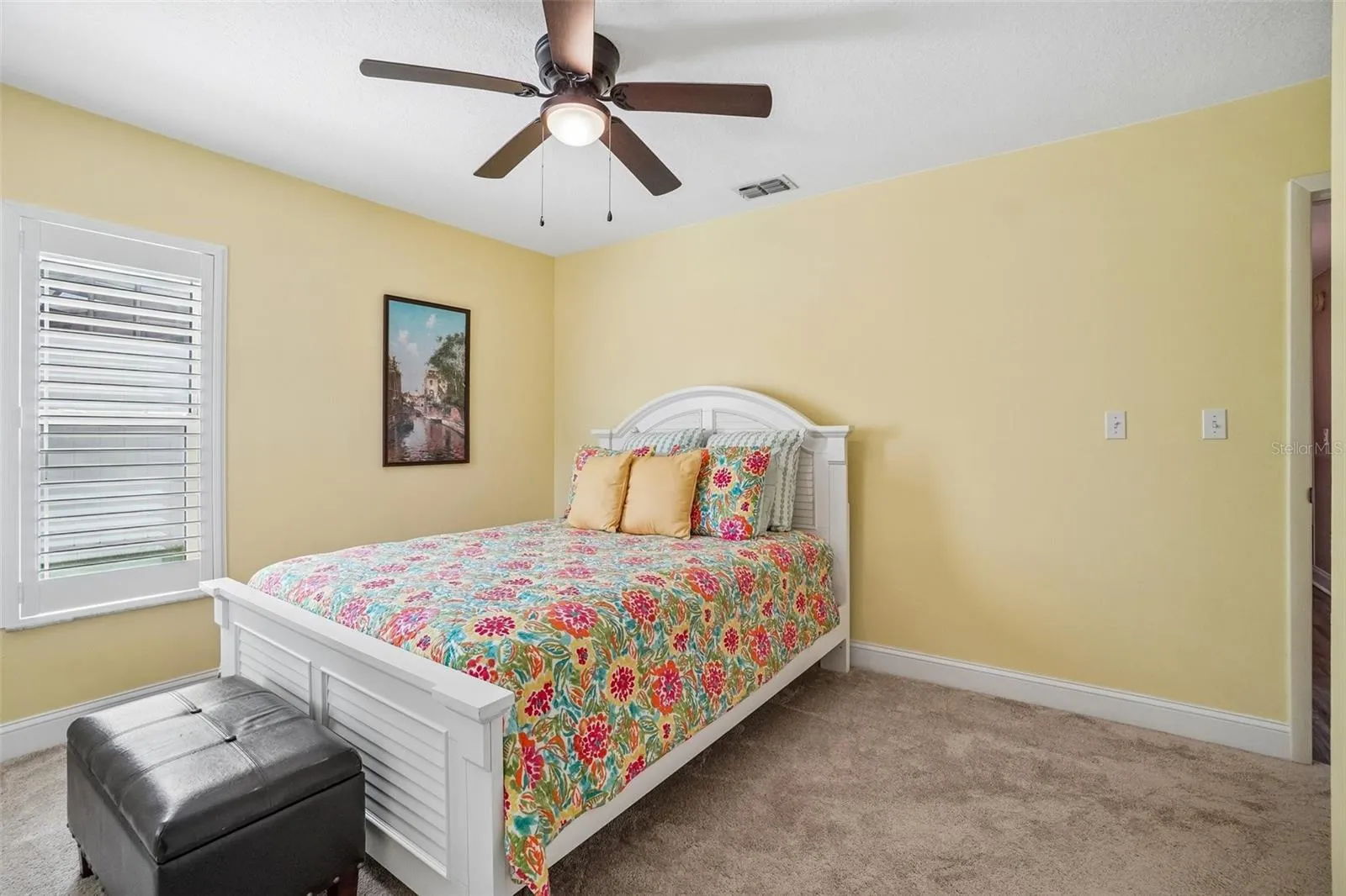 2nd Bedroom – This comfortable secondary bedroom offers soft carpeting, a ceiling fan, and a plantation-shuttered window that brings in natural light.
