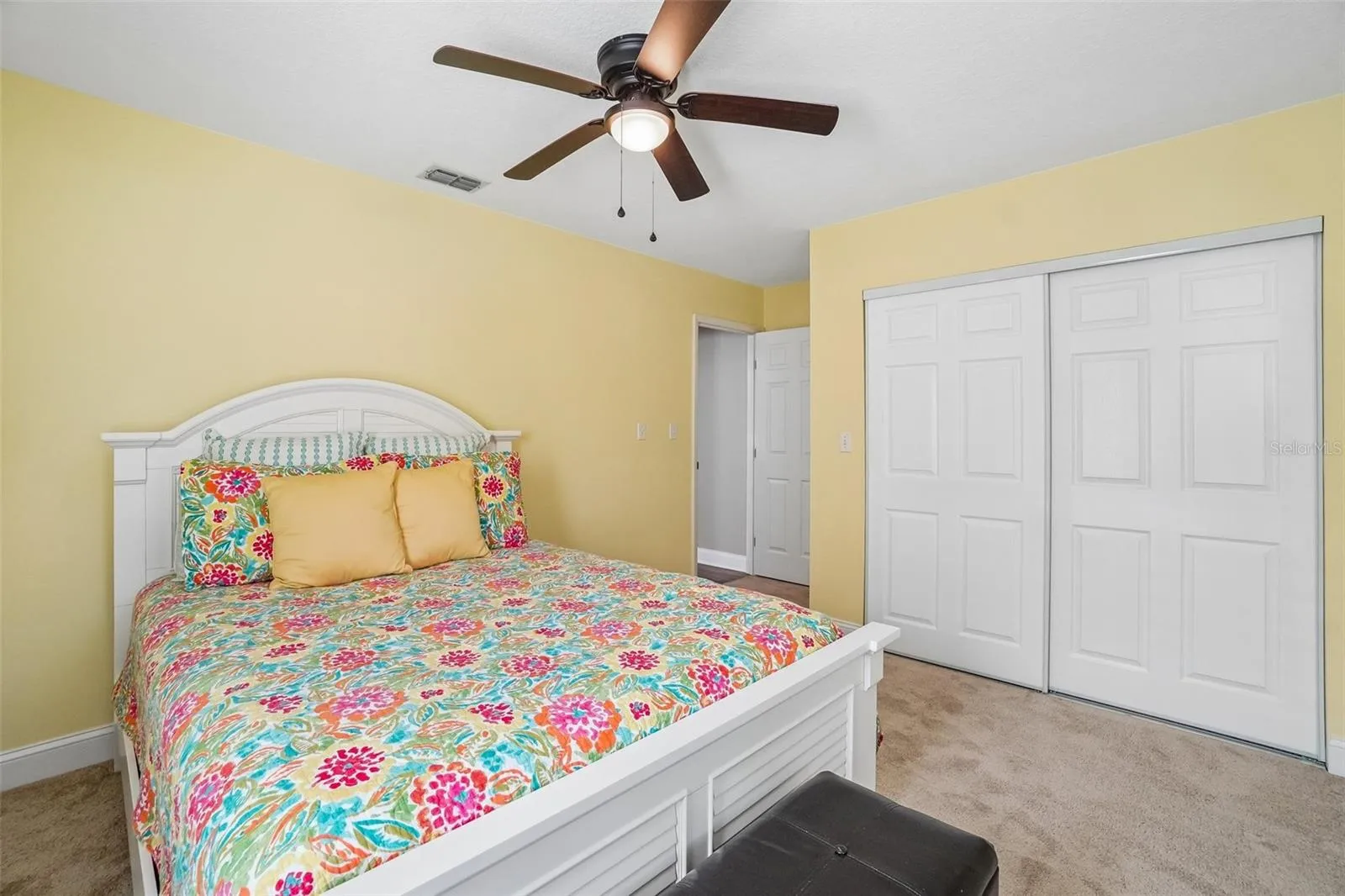 2nd Bedroom – Another view highlights the bedroom’s generous wall space, ceiling fan, carpeting, and wide sliding-door closet for convenient storage.