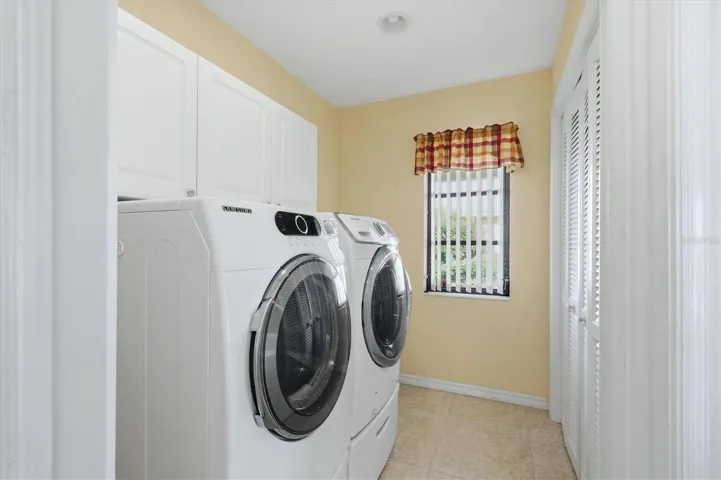Great laundry room with cabinetry, natural light and a large pantry closet all tucked behind a pocketing door