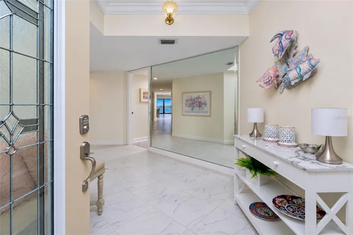 FOYER WITH LARGE TILE AND NICELY ACCENTED MIRRORED WALL