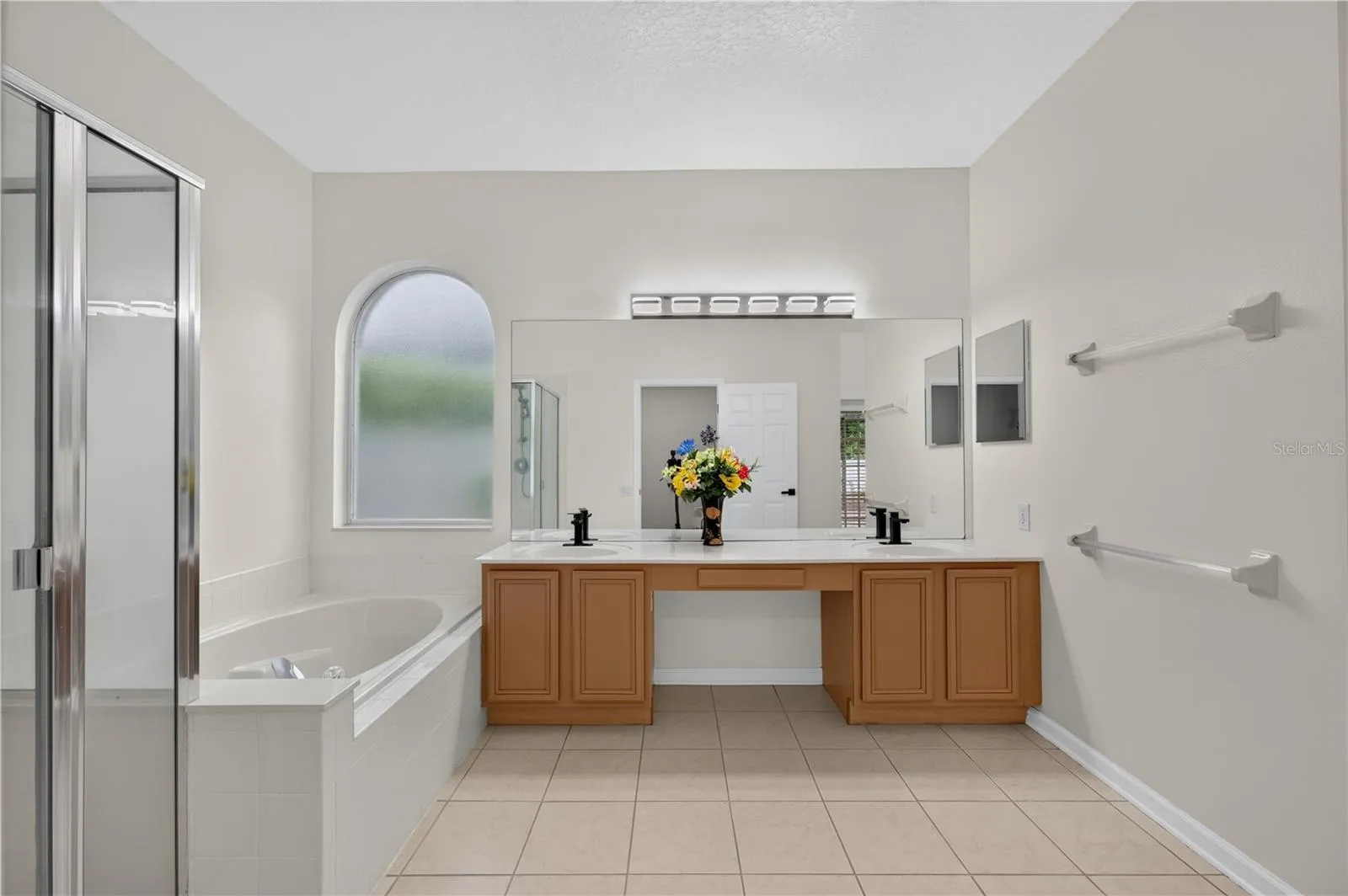 Primary bathroom featuring a garden tub, separate walk in shower, dual sinks, and direct access to the pool area.