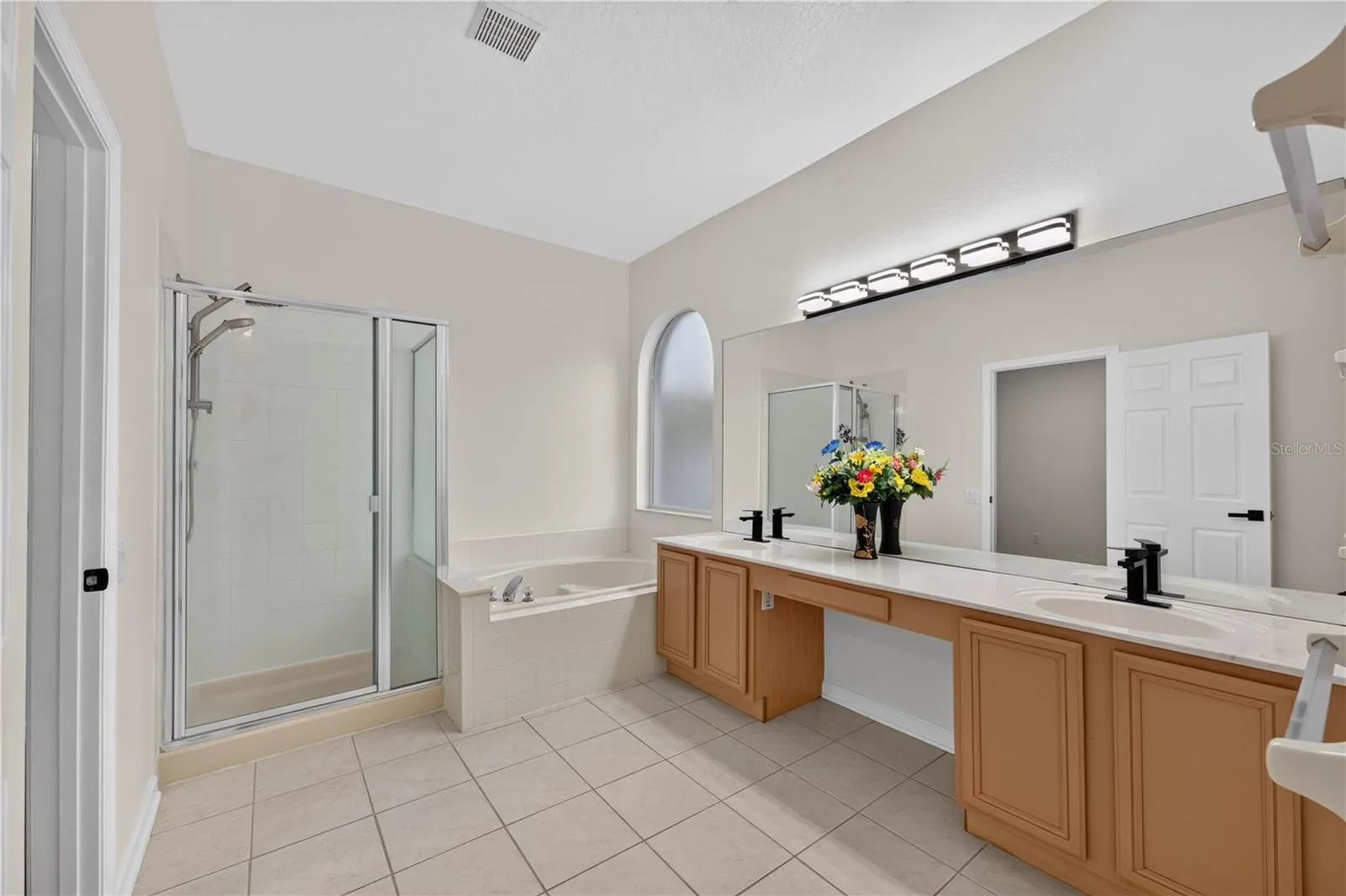 Primary bathroom featuring a garden tub, separate walk in shower, dual sinks, and direct access to the pool area.