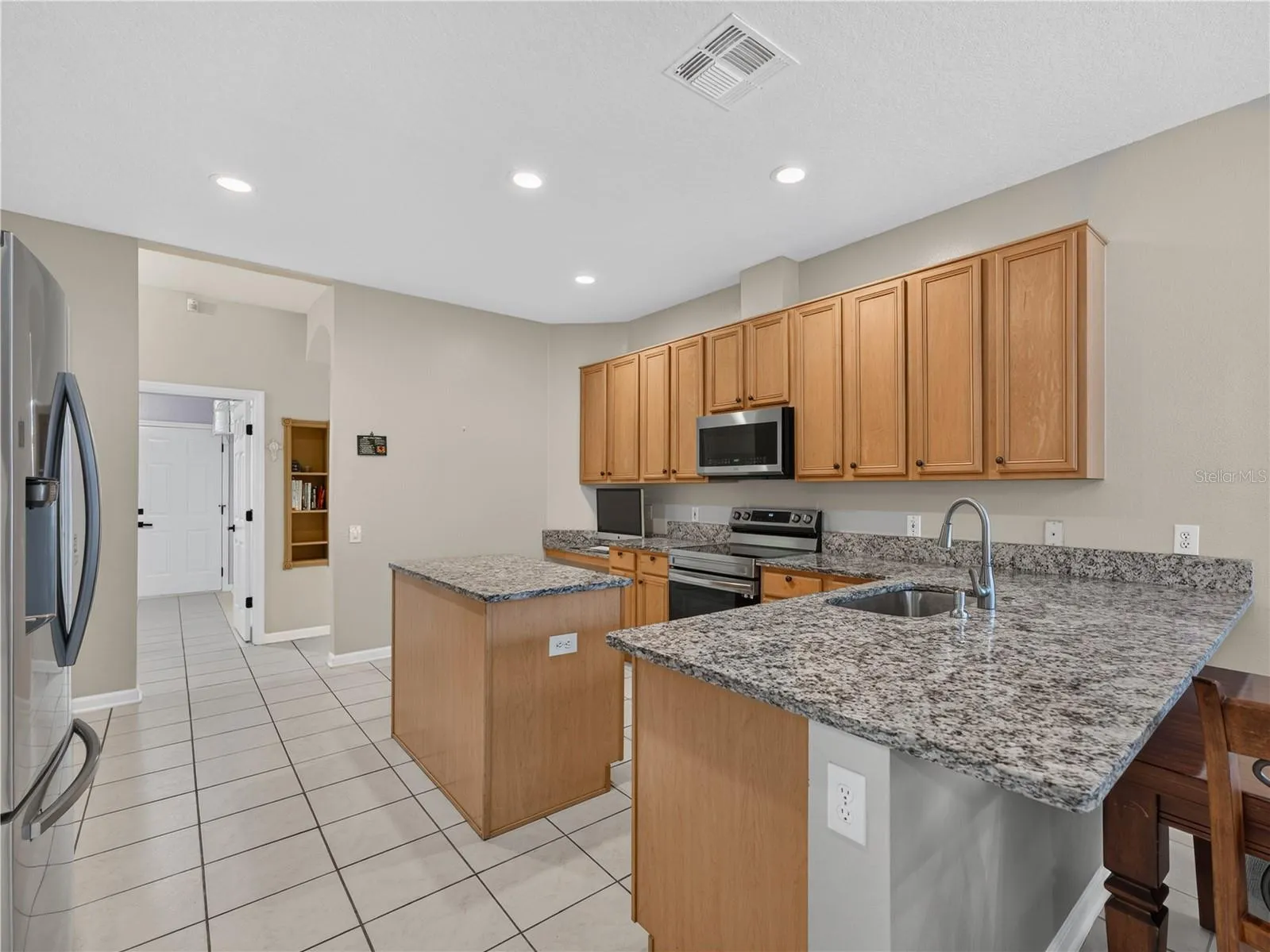 Kitchen featuring abundant cabinetry, granite countertops, stainless steel appliances, and a center island.  Great for entertainment.