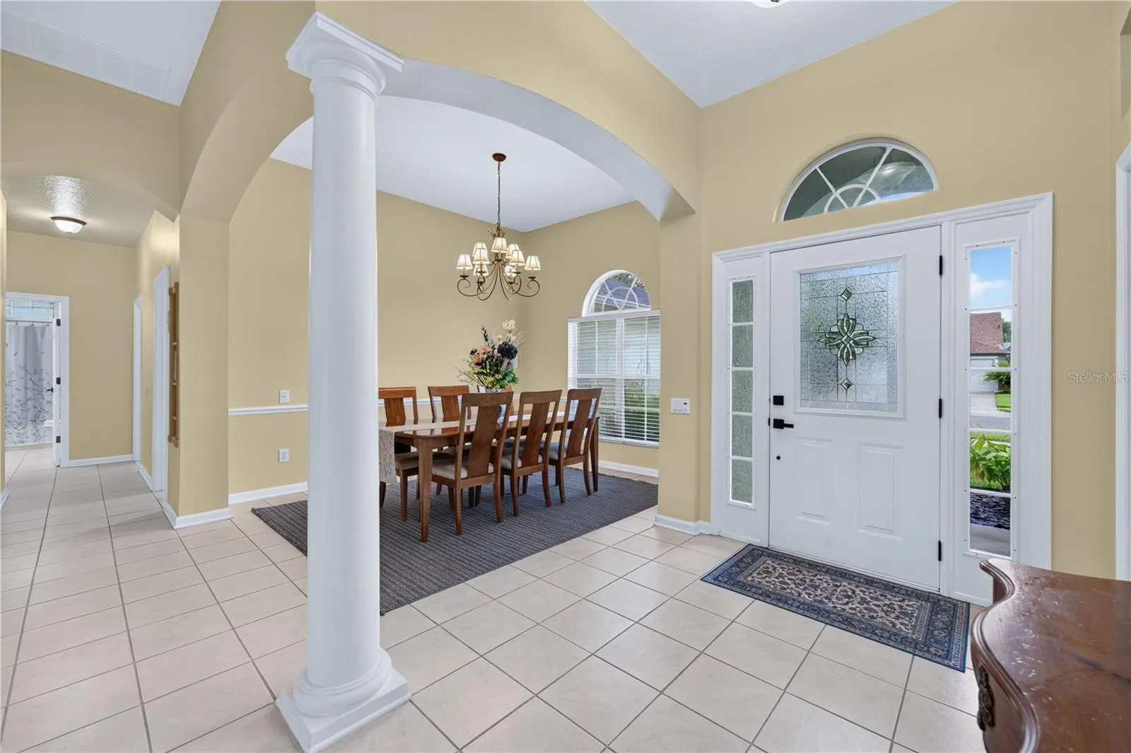 Welcoming entryway with high ceilings, decorative architectural details, and an adjoining formal dining room.