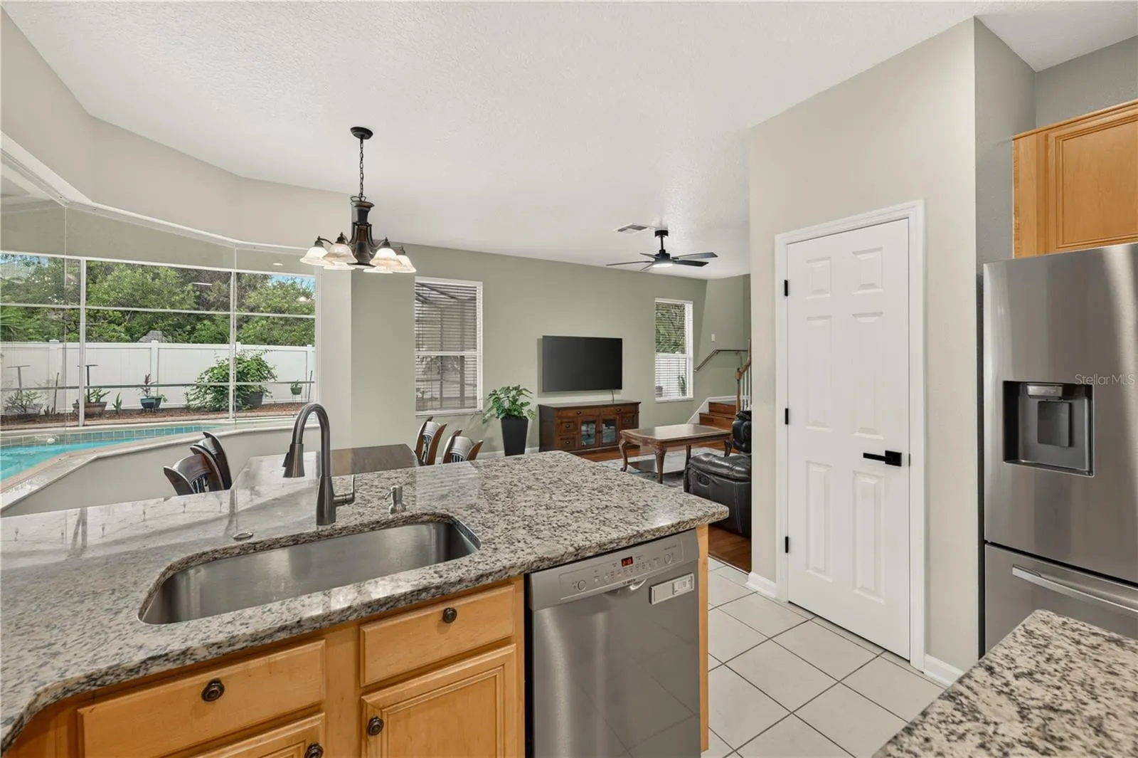 Open kitchen overlooking the family room and screened pool, featuring granite countertops and stainless steel appliances.