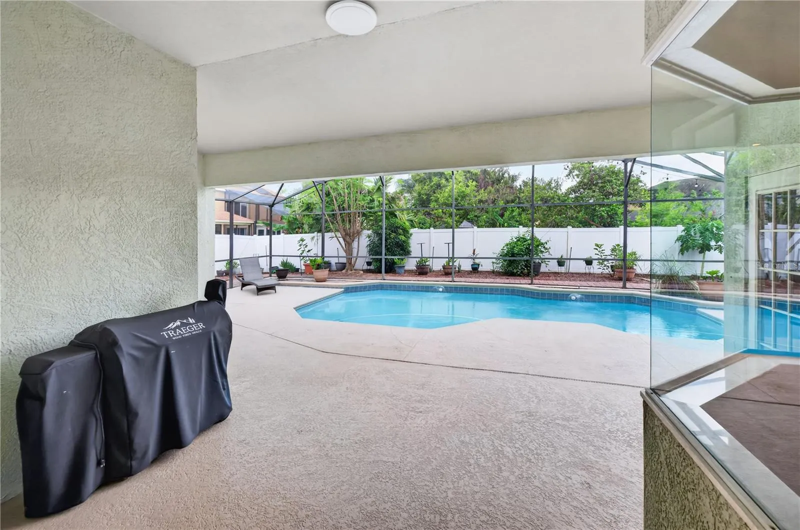 Covered outdoor living area overlooking the screened pool, perfect for relaxing and entertaining.