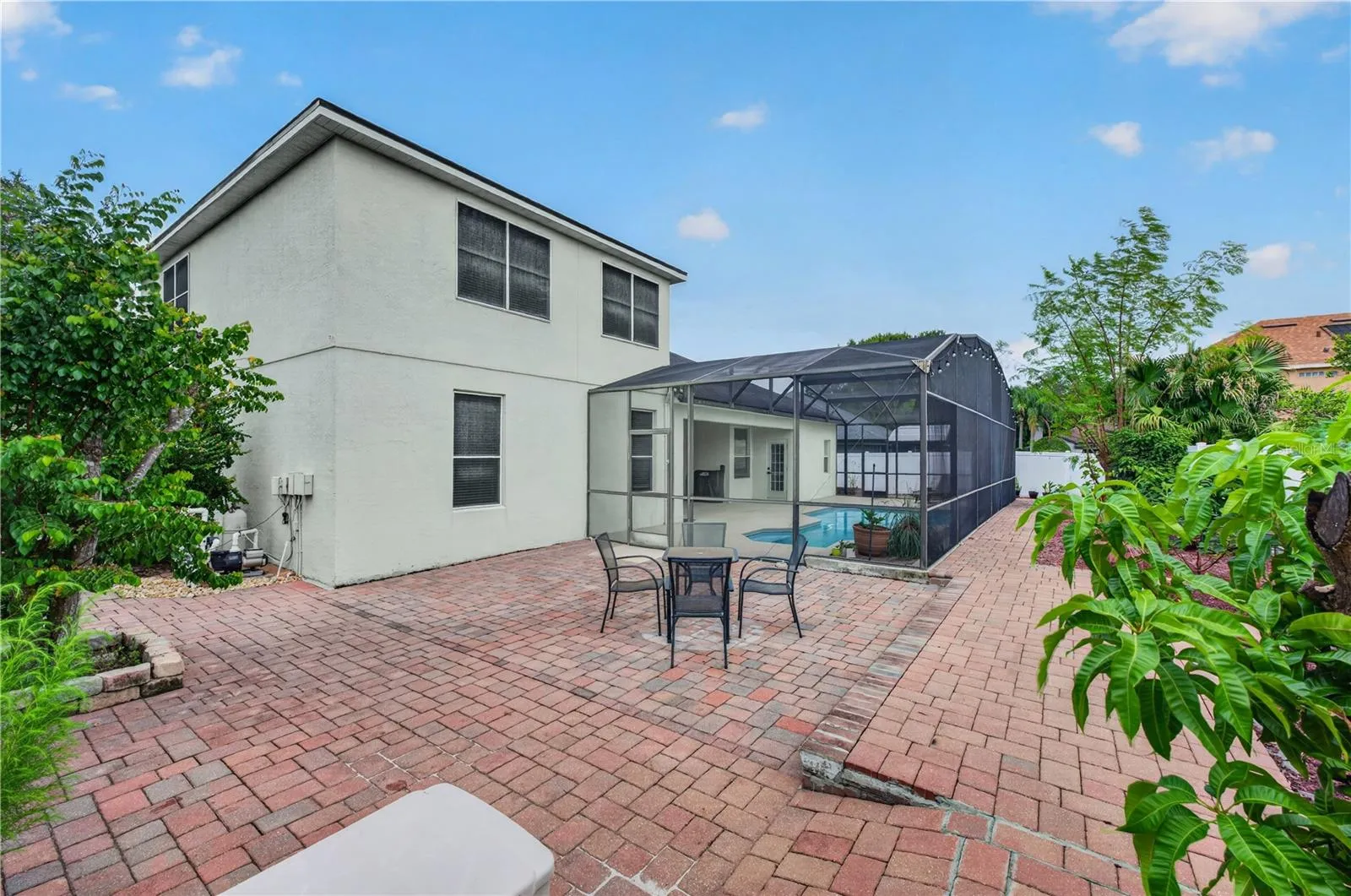 Fenced backyard with an expansive paver patio, mature landscaping, and plenty of room for outdoor entertainment.