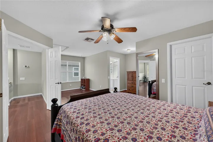 Spacious bedroom #5 with a separate sitting area, high ceilings, wood floorings, and a ceiling fan.