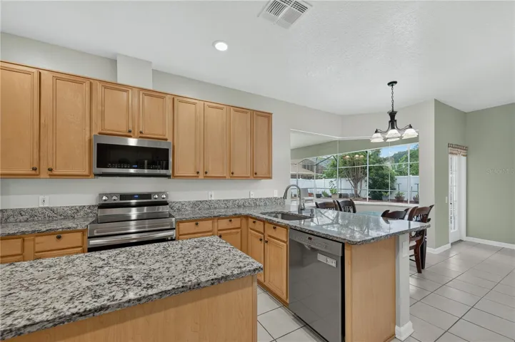 Kitchen featuring abundant cabinetry, granite countertops, stainless steel appliances, and a center island.  Great for entertainment.