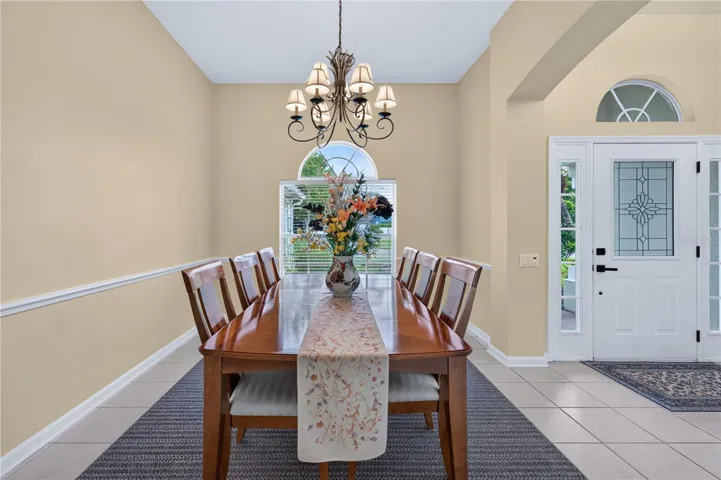 Elegant formal dining room with high ceilings, abundant natural light, and a decorative chandelier.