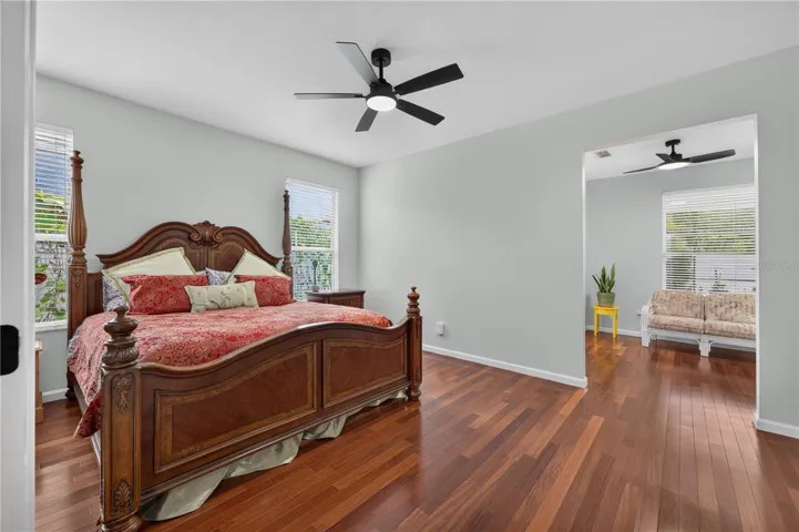 Spacious primary bedroom with wood flooring and a private sitting area.