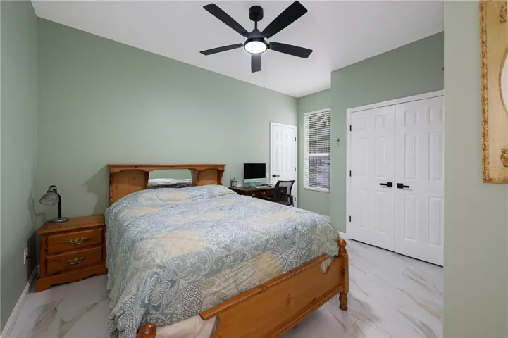 Bedroom #3 featuring high ceilings, a ceiling fan, tile flooring, and ample closet space.