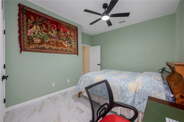 Bedroom #3 featuring high ceilings, a ceiling fan, tile flooring, and ample closet space.