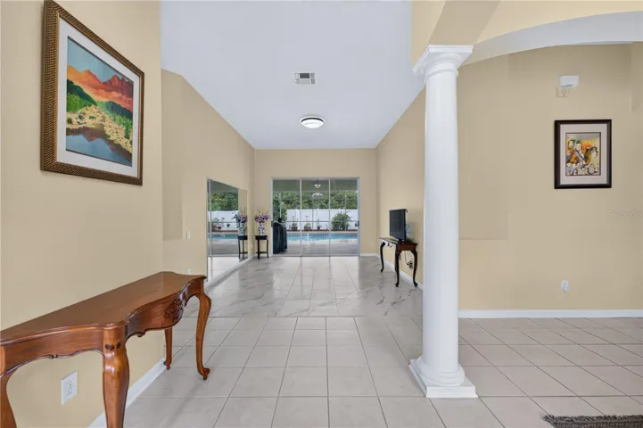Welcoming entrance leading into a spacious living room with high ceilings and direct access to the pool.