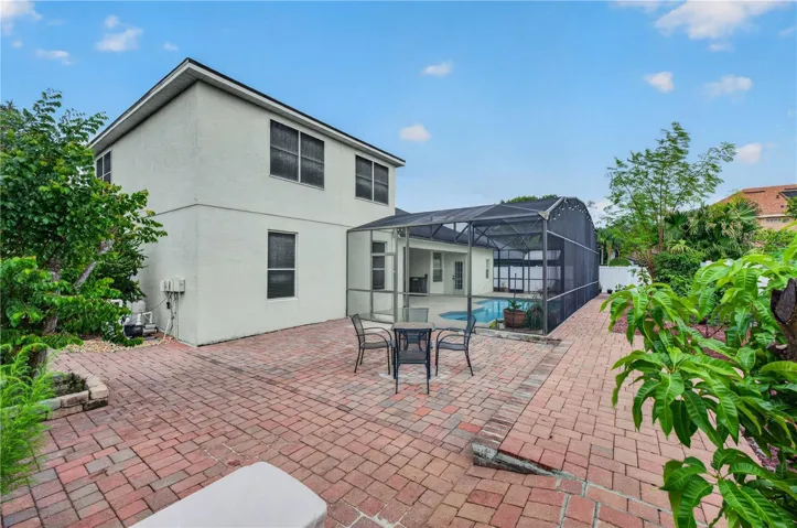 Fenced backyard with an expansive paver patio, mature landscaping, and plenty of room for outdoor entertainment.
