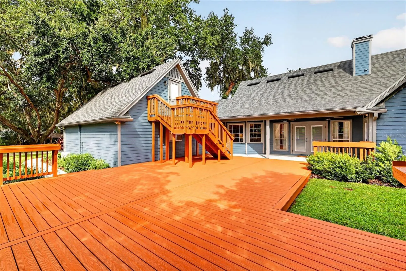 back deck area showing exterior of home, chimney view and stairs to office above garage.