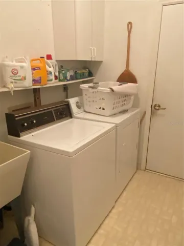 Laundry room indoor next to the garage door. Full size washer and dryer with ulitiy sink.