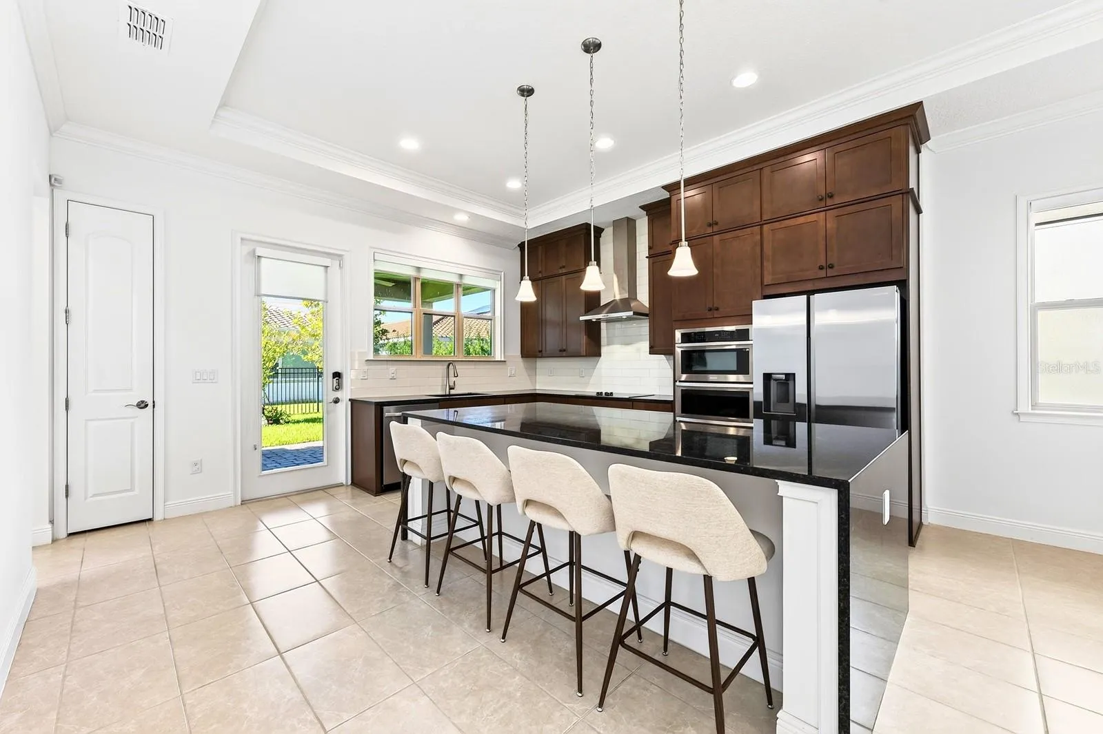 Beautifully appointed CHEF’S KITCHEN featuring rich SHAKER-STYLE CABINETRY, STAINLESS STEEL APPLIANCES, subway tile backsplash, pantry and a large WATERFALL ISLAND with breakfast bar seating.