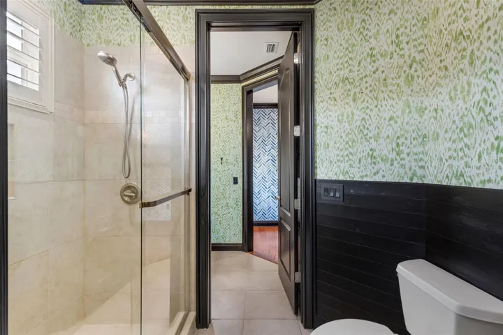 The shared part of this bathroom has a fully tiled shower with custom glass enclosure.