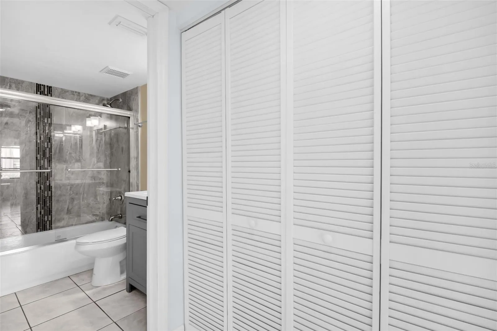 Hall closets with washer, dryer, utility with view of hall bath