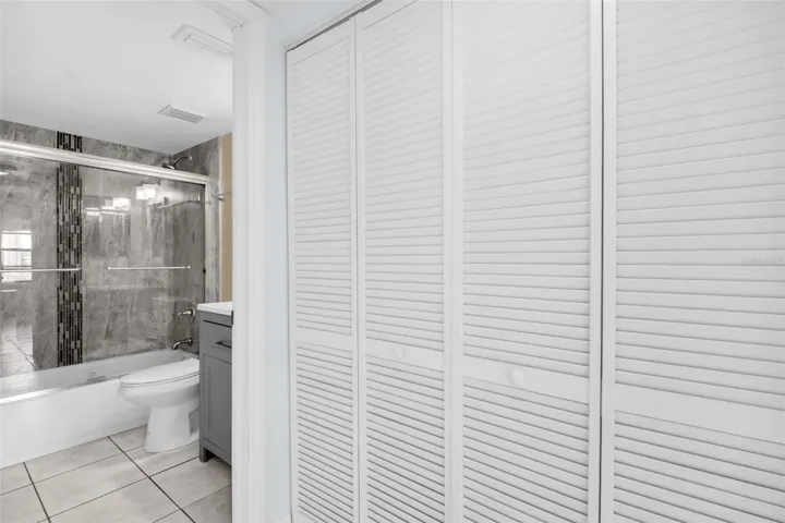 Hall closets with washer, dryer, utility with view of hall bath