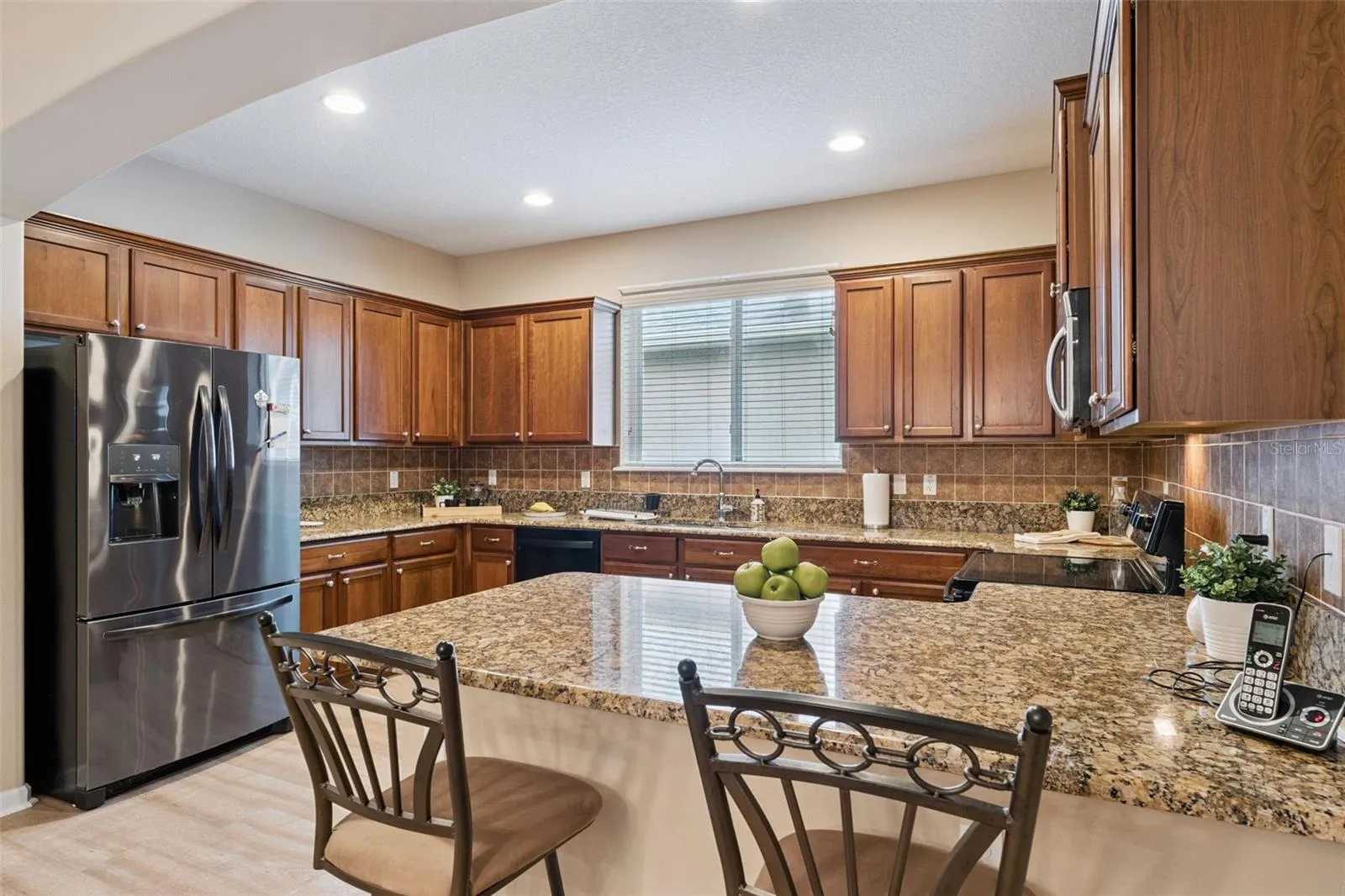 Kitchen w/ French door style refrigerator, electric glass top range & a breakfast bar
