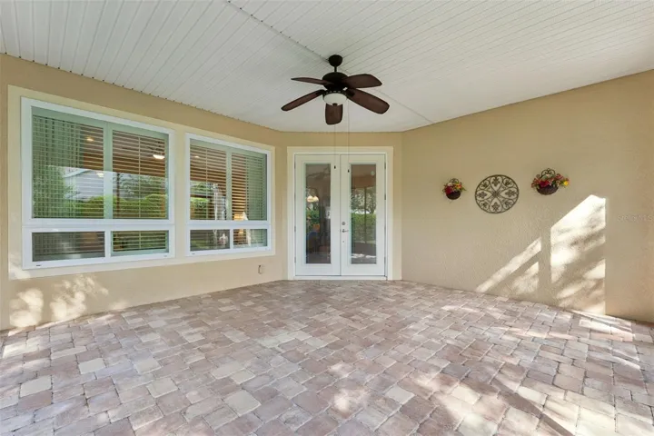 Screen enclosed covered patio w/ a ceiling fan & a double French door entry into the home