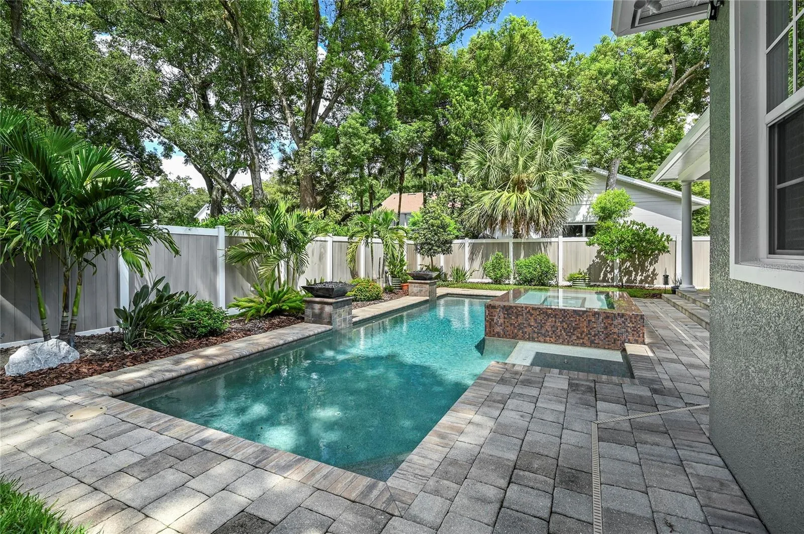 The back of the home looks out to beautiful skies and a towering tree canopy.