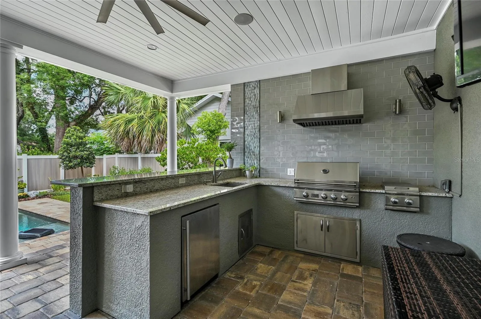 Cooks will love the professional gas grill with hood, side burner, a deep sink, and loads of stone counter space. Grab a drink from the fridge while you are sitting by the pool!