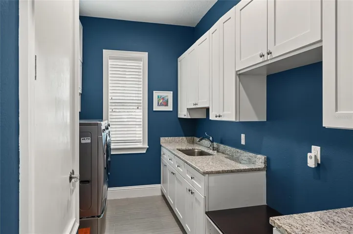 Natural light fills the laundry area, complete with sink and an abundance of storage.