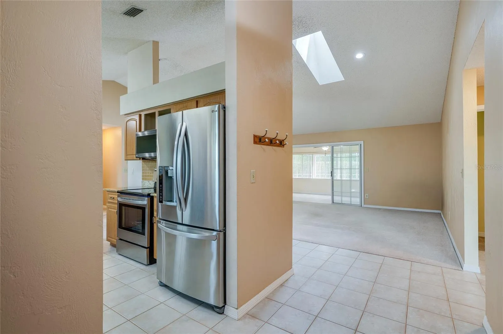 Functional kitchen nook outfitted with stainless steel appliances, modern tiling, and recessed lighting. Skylights overhead enhance the bright, open interior feel.