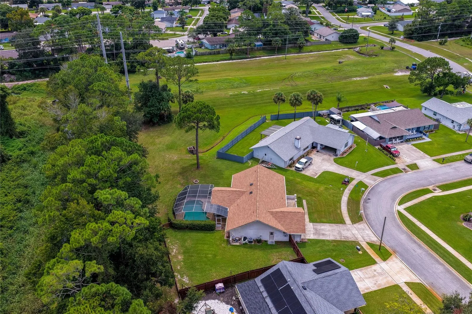 Angled aerial photo capturing the home placement, screened lanai, and generous lot size.