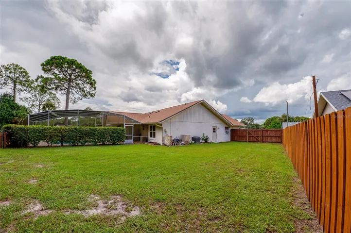 Full view of the rear elevation and spacious yard surrounded by a wooden privacy fence.