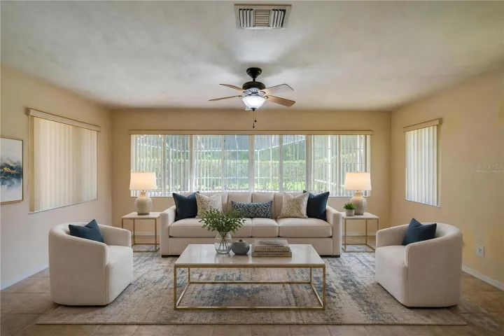 Virtually Staged - Bright enclosed sunroom equipped with light beige tile flooring, a ceiling fan, and wide windows fitted with vertical blinds for controlled light.
