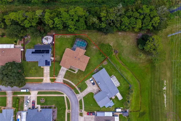 Overhead aerial shot outlining the expansive property boundary, screened pool enclosure, and surrounding green spaces.