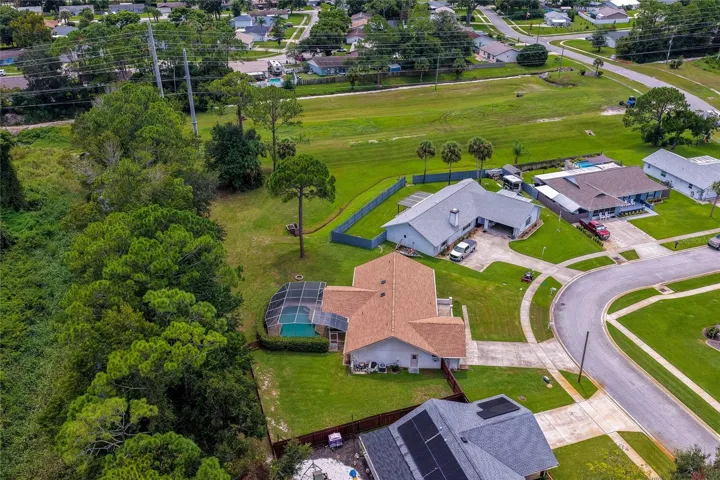Angled aerial photo capturing the home placement, screened lanai, and generous lot size.