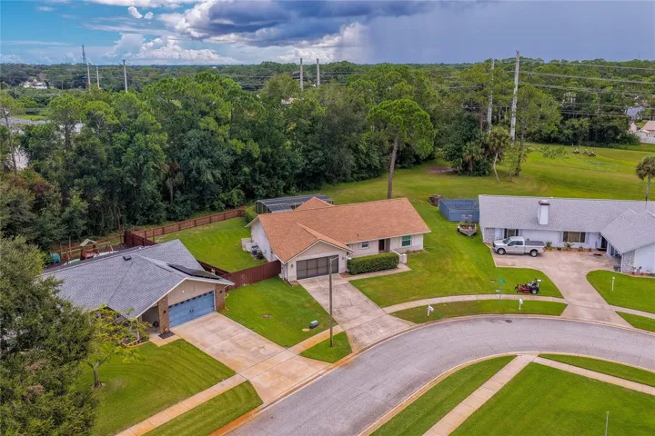 Elevated neighborhood view displaying the property's location along a quiet residential street bordered by mature trees.
