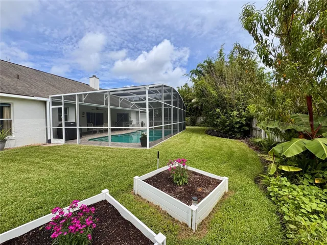 Spacious backyard with screened pool, mature landscaping and raised garden beds
