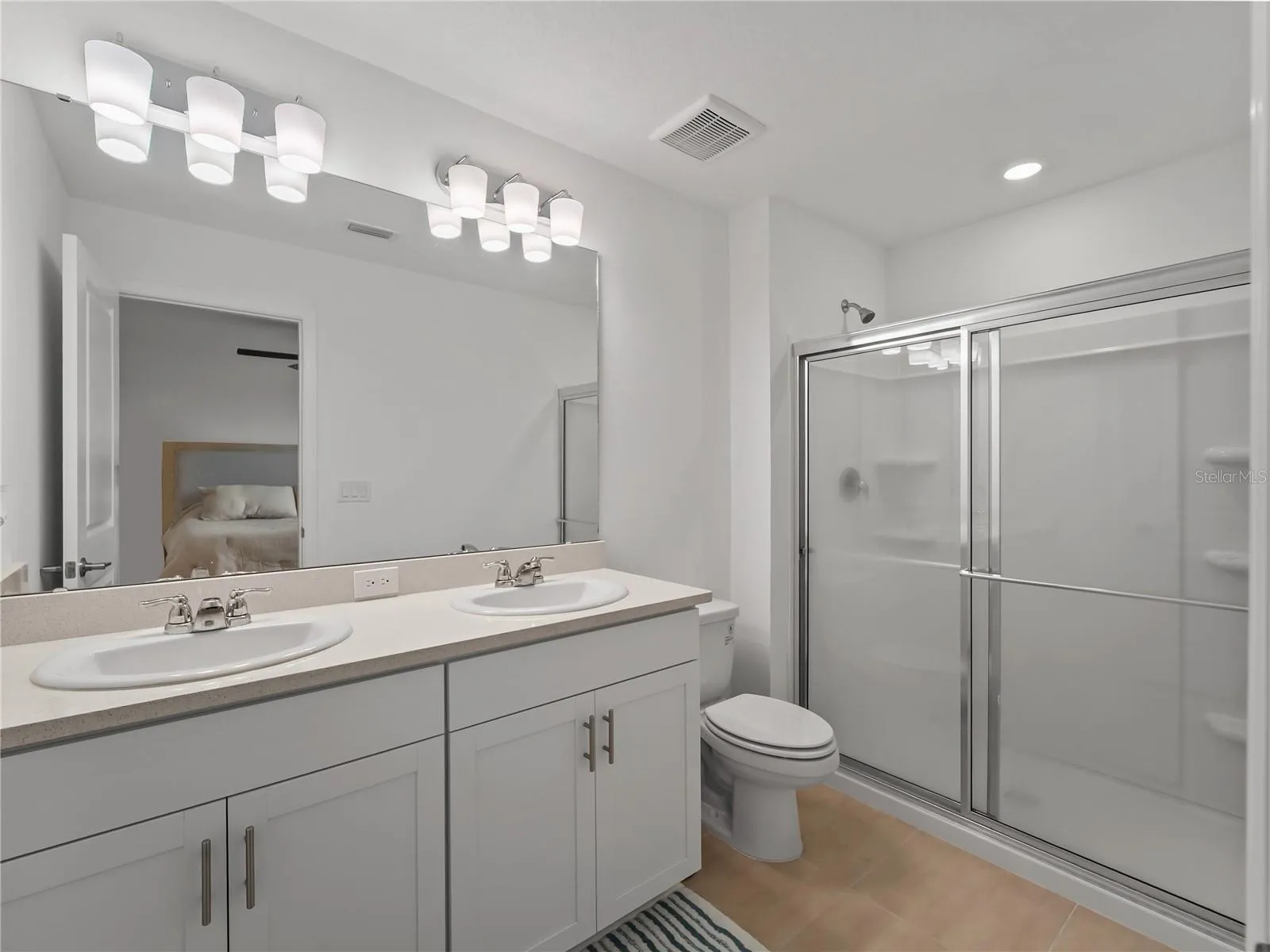 Primary bathroom with dual sinks, quartz counters, and shower