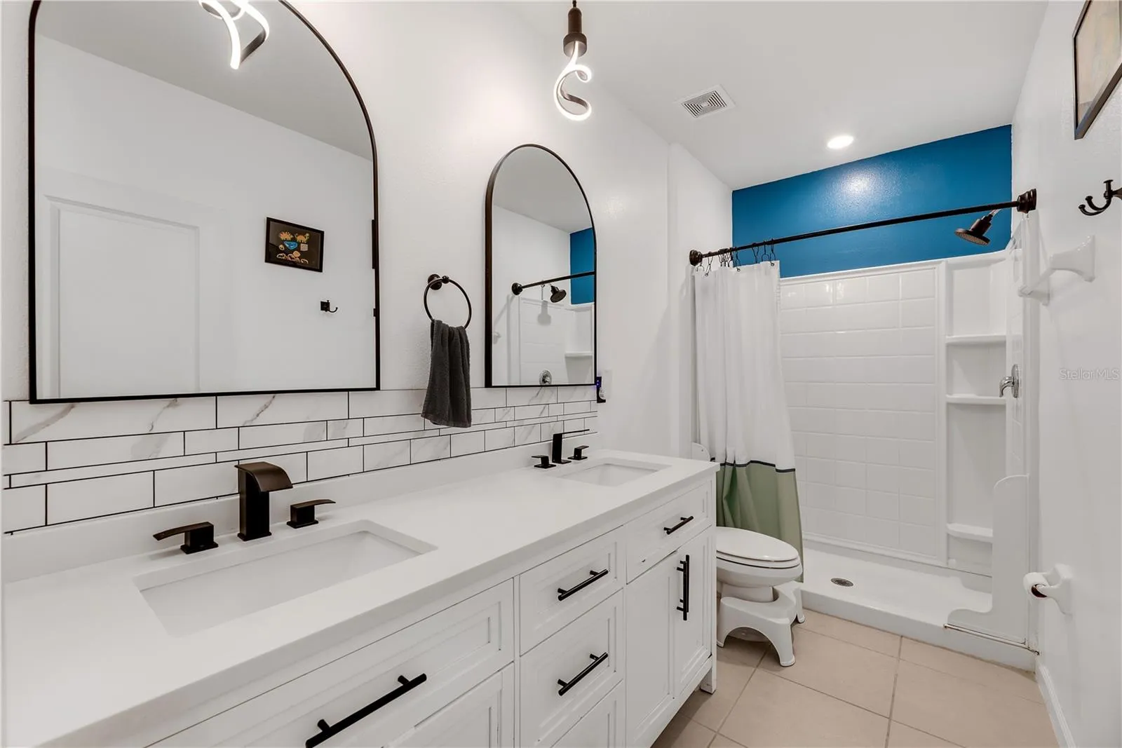 The spacious Owner's ensuite bath has double sinks, stone countertops, updated faucets and light fixtures and a walk-in shower