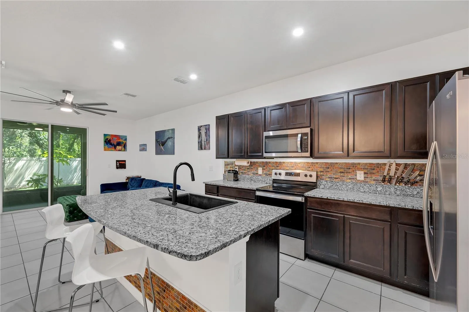 The kitchen showcases granite countertops, stainless appliances, and a spacious center island with a large single basin granite sink and bar seating, making meal preparation effortless.