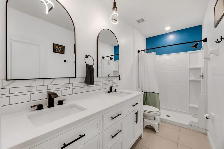 The spacious Owner's ensuite bath has double sinks, stone countertops, updated faucets and light fixtures and a walk-in shower