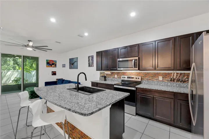 The kitchen showcases granite countertops, stainless appliances, and a spacious center island with a large single basin granite sink and bar seating, making meal preparation effortless.