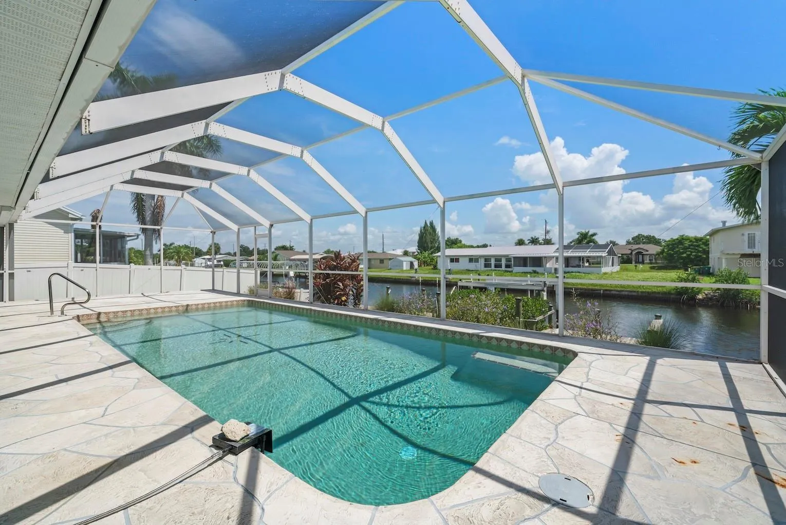 Large pool and lanai area overlooking canal, dock, and private boat lift.