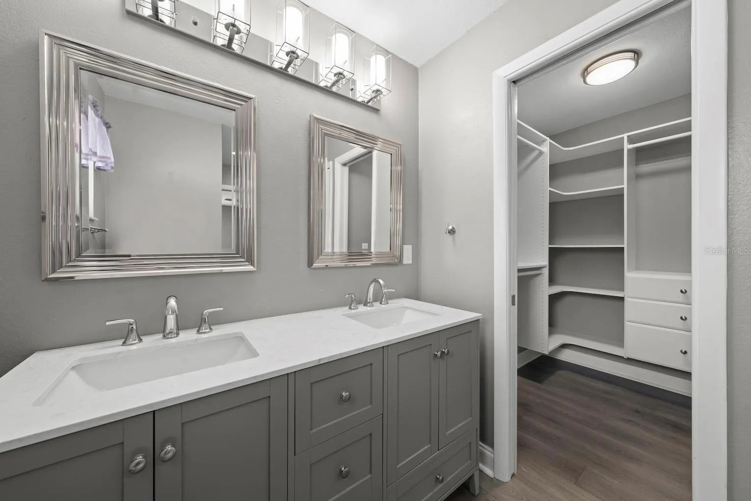 Primary bathroom double sink vanity showing 1 of 2 walk-in closets.