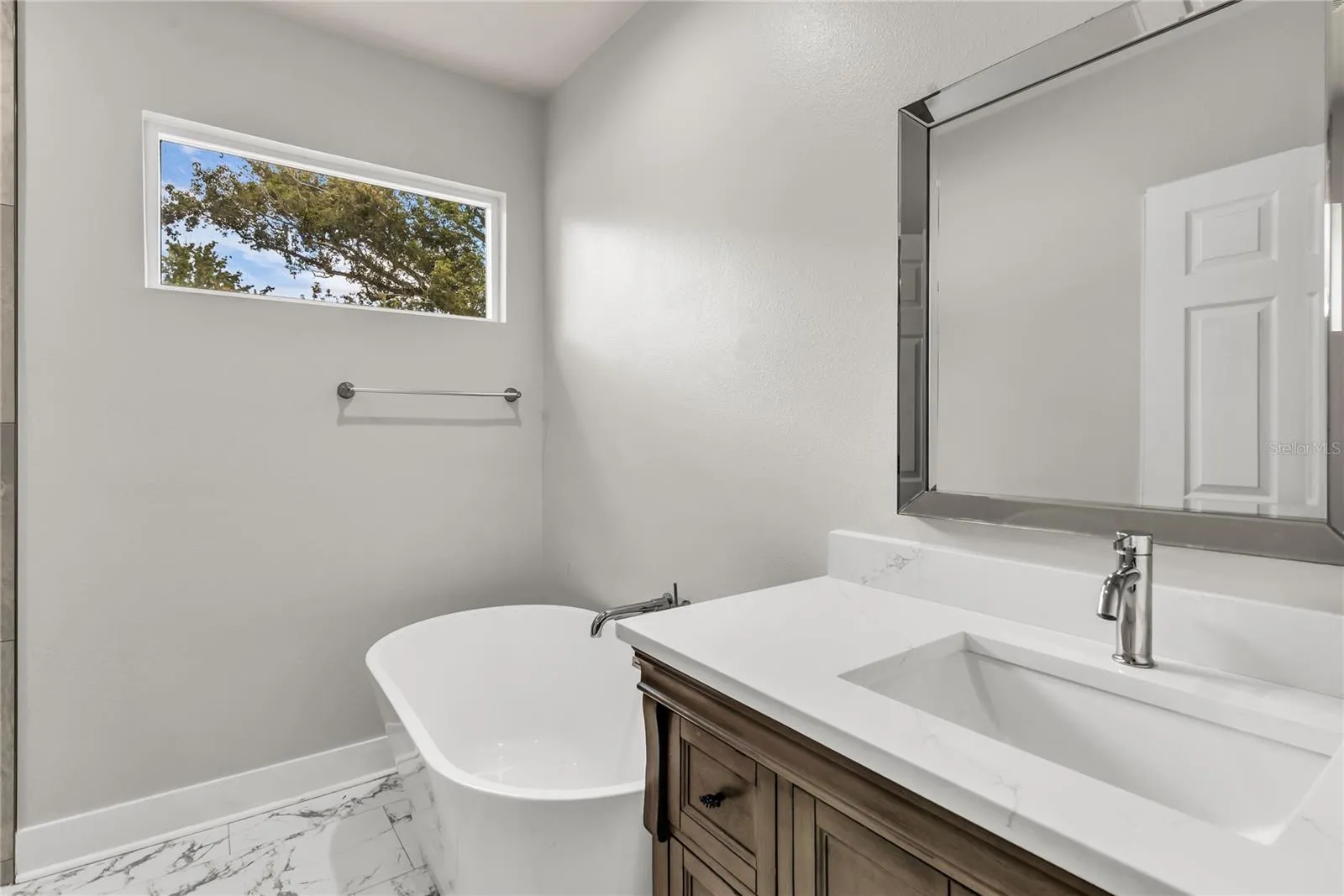 Primary bath features standalone vanity with stone countertop, soaker tub and tiled standalone shower.
