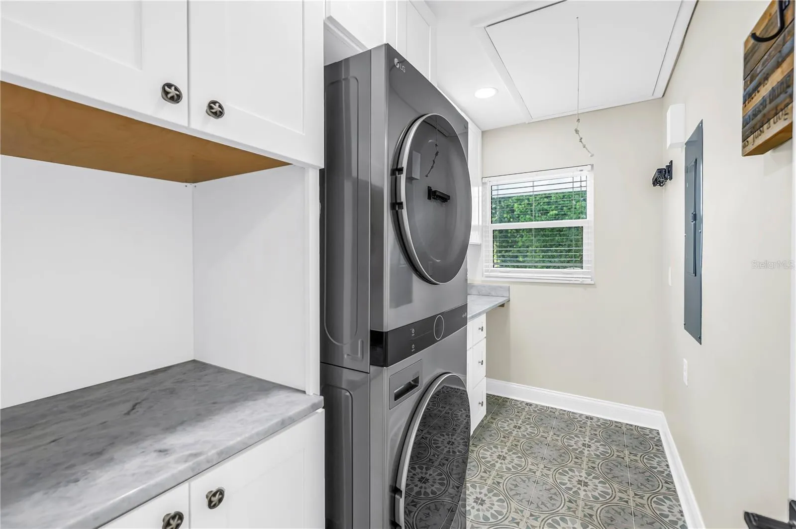 Oversized laundry room with Shaker cabinetry, quartz countertops (all match kitchen), utility sink, storage and FULL size stackable LG ThinQ high efficiency washer and dryer.
