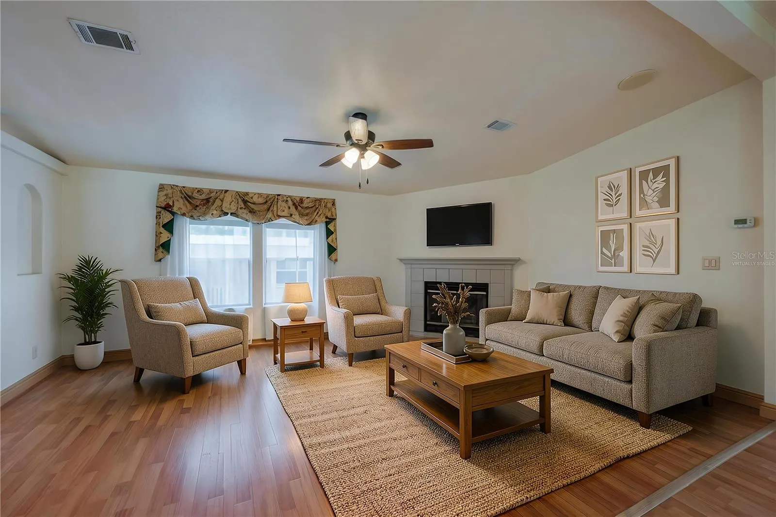 Virtually Staged...Bright living room offers plenty of flexibility for seating and entertaining, with a fireplace, ceiling fan, and large front-facing windows.