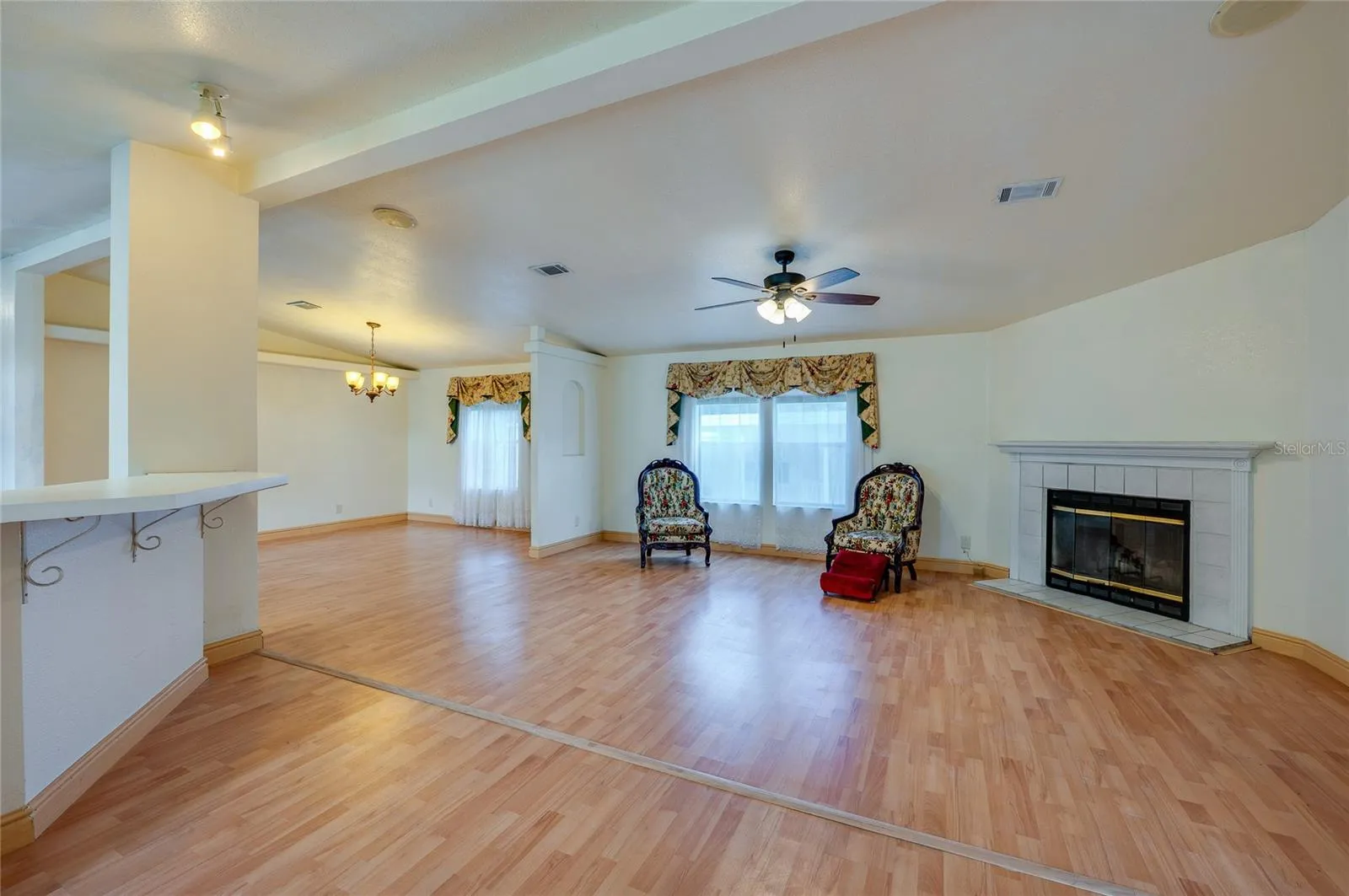 Another view highlights the generous living space, large windows, fireplace, and open sightlines into the dining area.